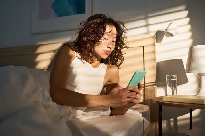 Casual worker resting at home in bed using smartphone to book a sick leave certificate through OMC Health