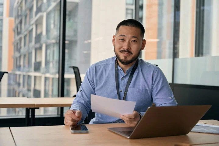 Professional reviewing a job offer alongside a laptop before completing a pre-employment medical certificate
