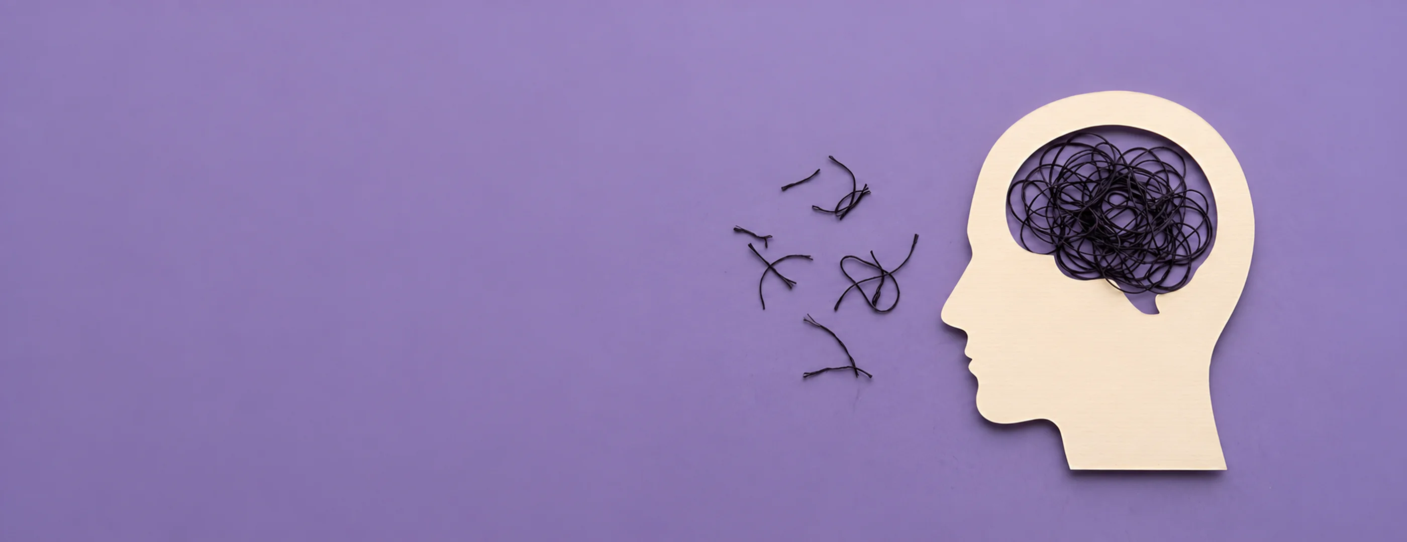 Paper cutout of a head silhouette filled with a tangled dark thread, representing racing, overwhelmed thoughts in ADHD burnout