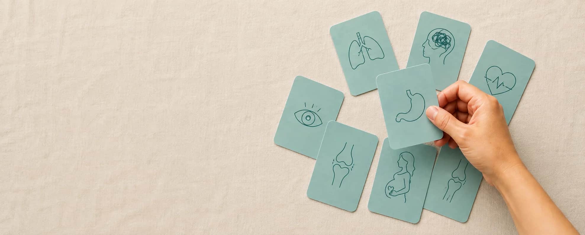 Overhead flat lay of minimal icon cards on linen fabric — lungs, mind, stomach, joint — representing browsable health condition categories, a hand picking one up — Medical Certificates for Common Heal