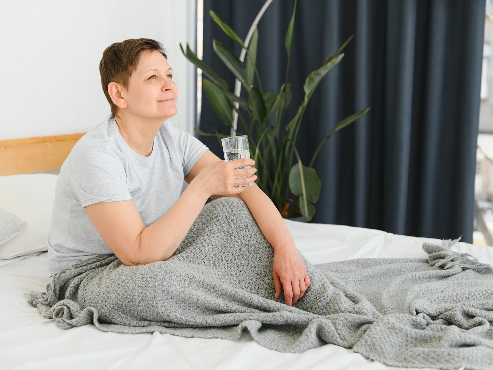 Woman resting in bed at home with a glass of water during several days of sick leave