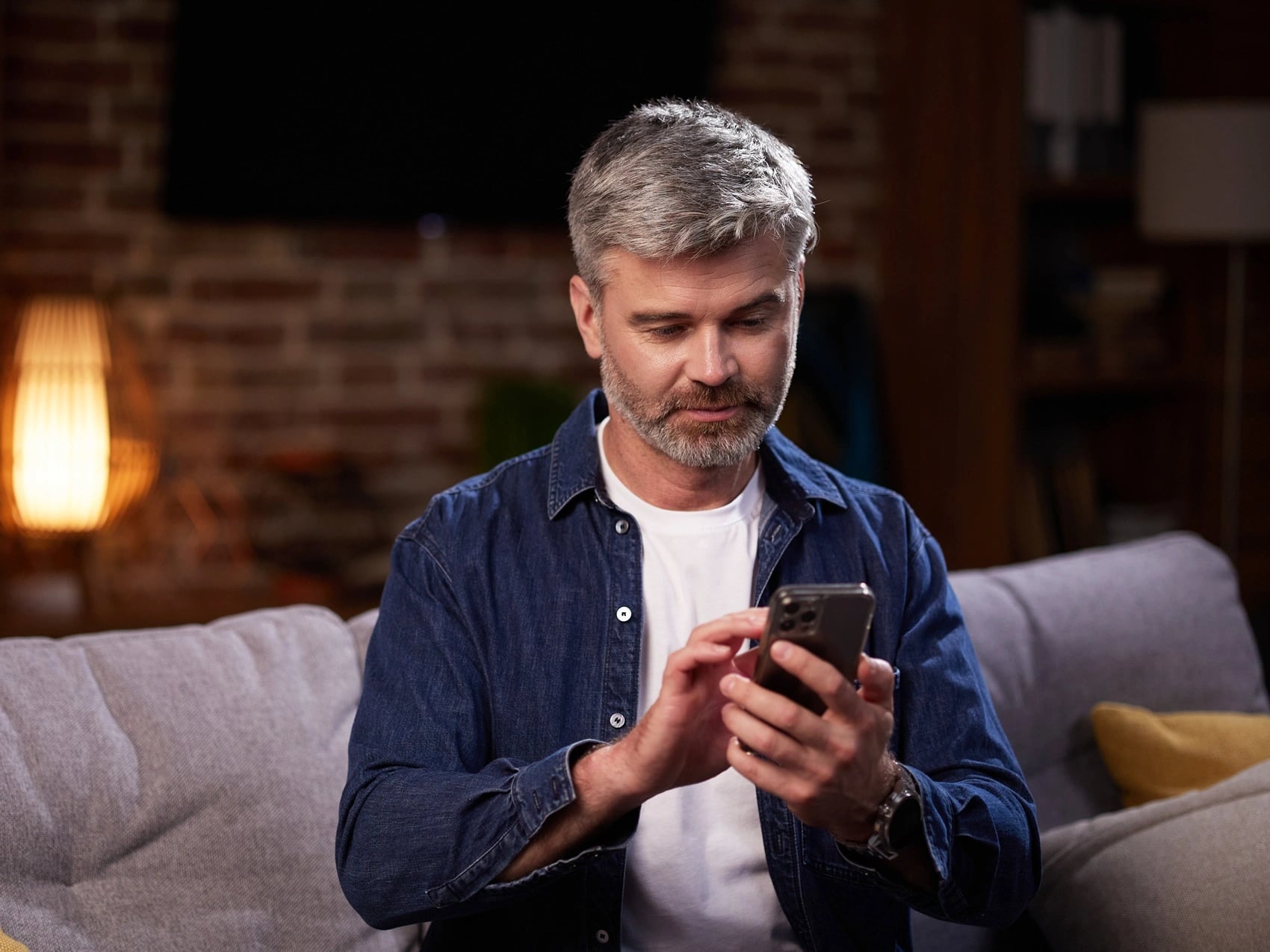 Evening at home with lamps on as a man uses his phone to request an after hours medical certificate.