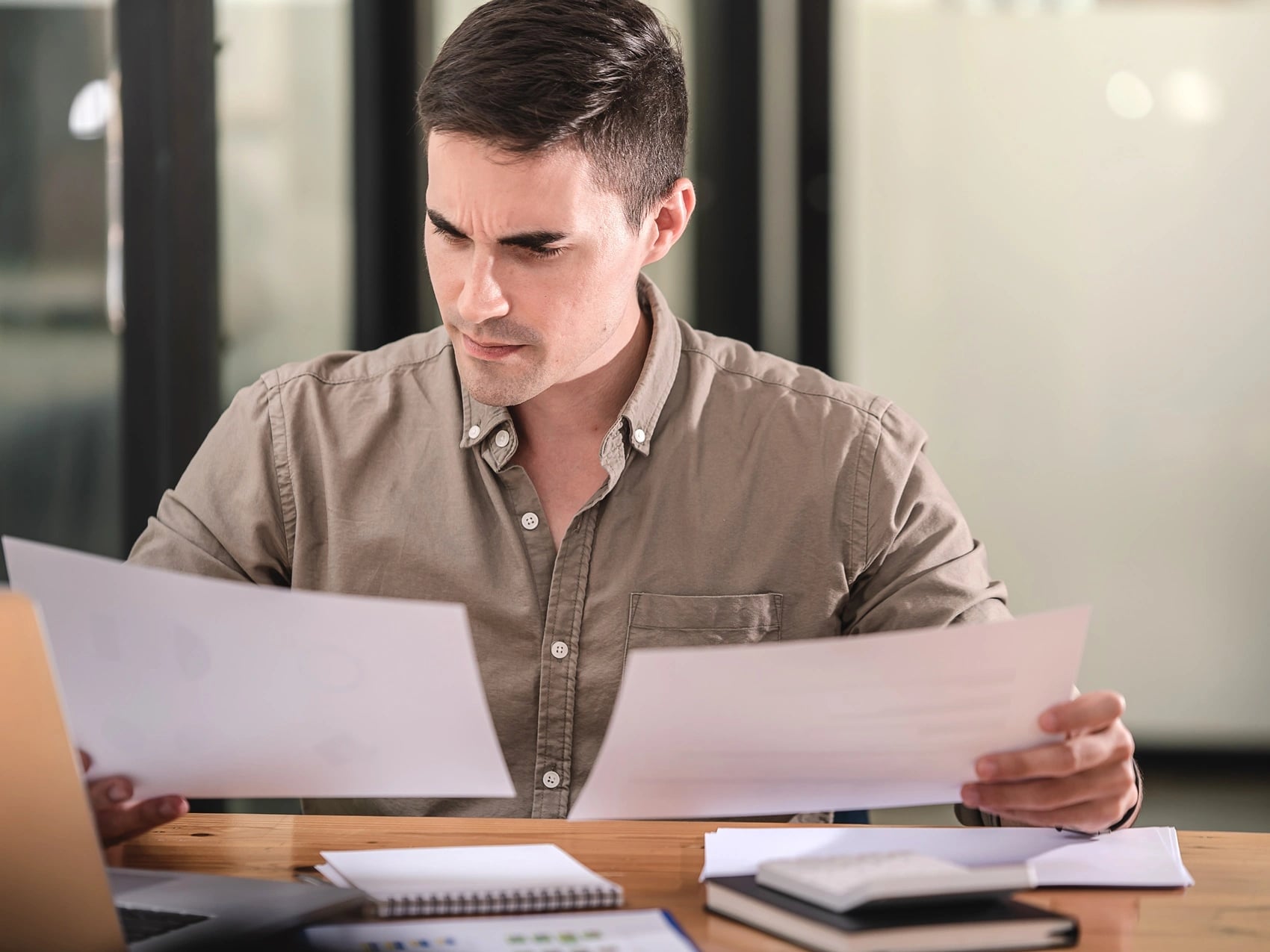 Man at a desk comparing two blank documents, weighing a medical certificate against a statutory declaration.