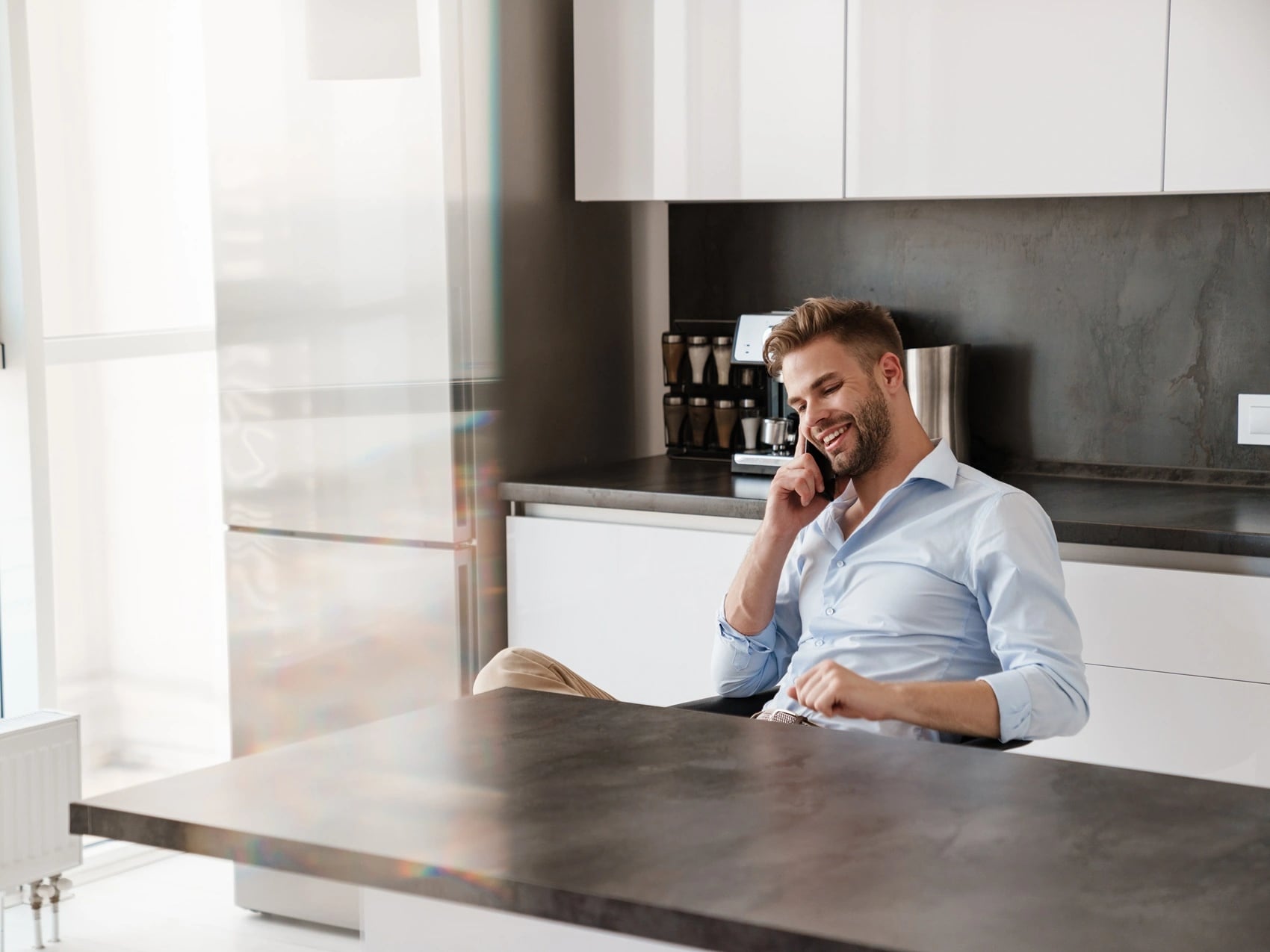 Man at a kitchen bench speaking on his phone, showing a consultation without a video call.