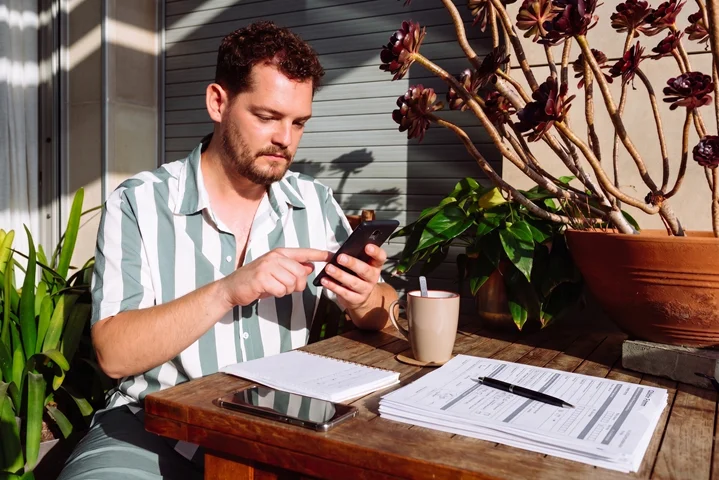Worker relaxing on a home patio reviewing paperwork and their phone during a WorkCover Queensland Certificate of Capacity claim