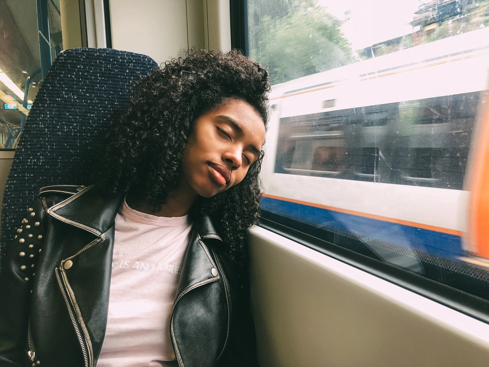 Student resting against a train window while travelling home