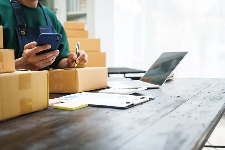 Warehouse worker at home reviewing paperwork and their phone while completing a WorkSafe Victoria Certificate of Capacity